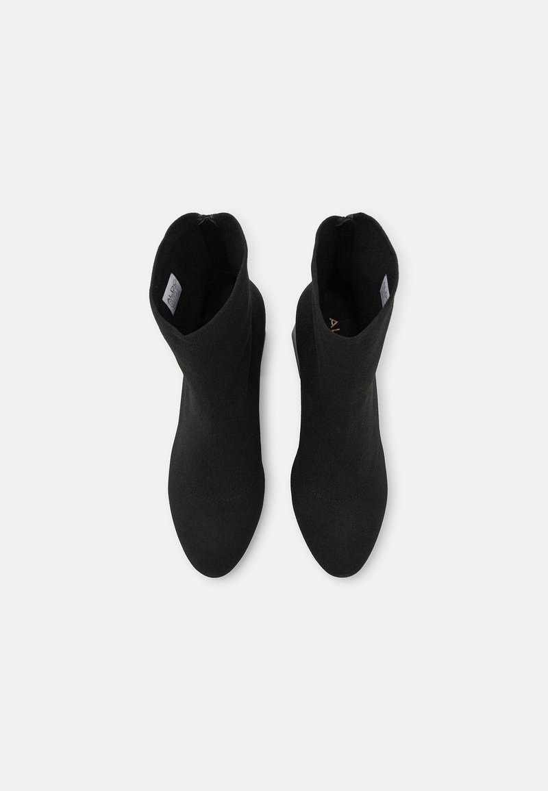 Schwarze Knöchelstiefel aus dehnbarem Material, mit spitz zulaufendem Design und einer glatten Oberfläche in minimalistischem Stil.