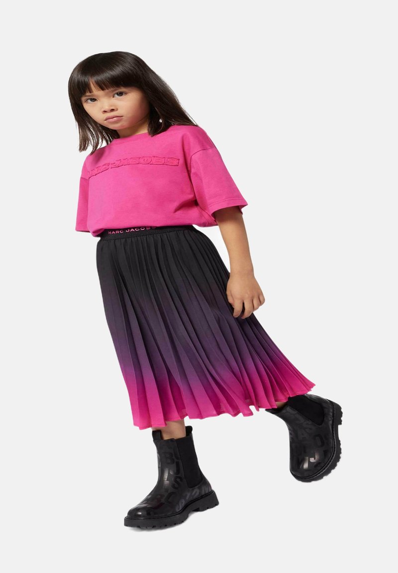 Roze katoenen T-shirt met reliëftekst, gecombineerd met een geplooide rok in een verloop van zwart naar roze, en zwarte enkellaarsjes met logo-accenten.