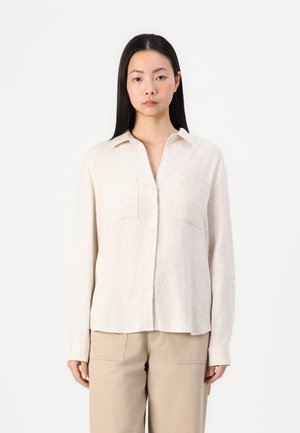 Light beige long-sleeve shirt made of textured fabric with a relaxed fit, button placket, two chest pockets, and a collared neckline.