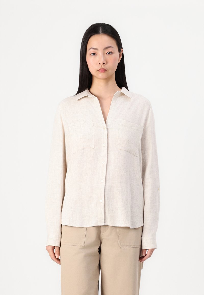 Lichtbeige langekleurige shirt met lange mouwen, gemaakt van textuurstof met een relaxte pasvorm, knoopsluiting, twee borstzakken en een kraag.
