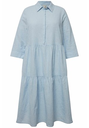 Lichtblauwe linnen jurk met een kraag met knopen, driekwart mouwen, gelaagde uitstraling en een ontspannen pasvorm. Gelaagd weefsel voegt diepte toe.