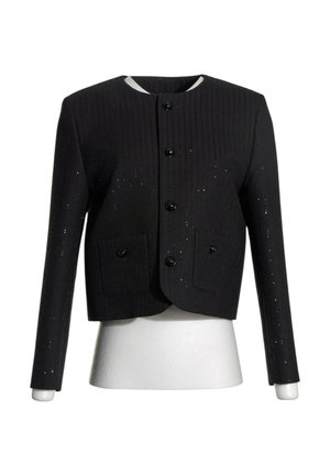 Chaqueta corta negra con mangas largas, cuello redondo, cuatro botones delanteros y dos bolsillos con botones en un maniquí blanco.