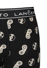 Czarne bokserki w nadruk w beżowe kontrolery do gier i kierownice. Miękka tkanina z czarnym elastycznym pasem.