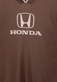 Bruine sportshirt met een gestructureerde afwerking, met een wit "Honda" logo en embleem dat prominent op de voorkant is weergegeven.