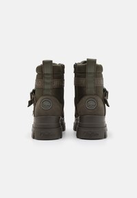 Zelené vojenské boty ve stylu s texturovaným povrchem, se zipy, nastavovacími popruhy a logem na zadní části. Hranaté podrážky.