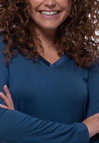 Camicia a maniche lunghe blu con scollatura a V. Tessuto liscio con una leggera lucentezza, maniche aderenti e senza motivi o hardware visibili.