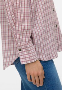 Geruite shirt met rode en witte strepen, lange mouwen, knoopdetails op de manchetten, gemaakt van zachte stof, gecombineerd met blauwe denim jeans.