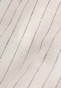 Light beige fabric with thin, evenly spaced vertical black stripes and a slightly textured, woven surface.