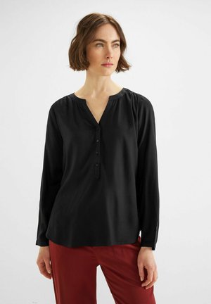 Blusa negra de manga larga con escote en V, botonera y detalle fruncido en los hombros; tejido suave y ligero.