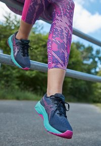 Baskets de sport avec une tige bleu marine, des accents roses et une semelle teal. Matériau en maille léger avec une finition texturée pour la respirabilité.