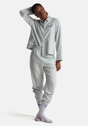 Set di pigiama a righe in verde chiaro e viola. La camicia ha un colletto e bottoni, mentre i pantaloni hanno una vita elastica. Include calzini lavorati a maglia.