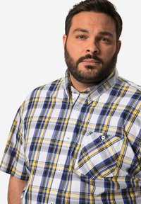 Camicia a maniche corte, con bottoni, in un motivo a quadri blu, giallo e bianco. Presenta una tasca sul petto e un classico design colletto.