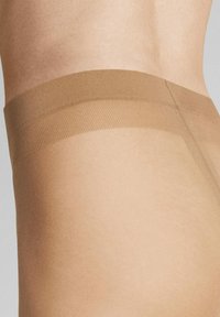 Beige, transparente Strumpfhosen zeichnen sich durch eine glatte Textur und einen breiten, elastischen Taillenbund für zusätzlichen Komfort aus. Das Design ist nahtlos und hat ein minimalistisches Erscheinungsbild.