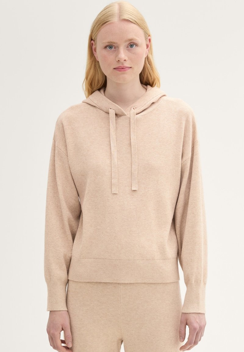 Felpa con cappuccio color beige chiaro realizzata in tessuto morbido. Presenta una vestibilità comoda, polsini a costine e una tasca a marsupio frontale.