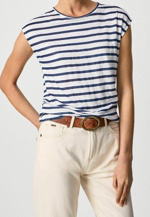 Person wearing a white and navy striped sleeveless shirt tucked into off-white pants with a brown leather belt with an oval buckle.