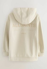 Krémová mikina s kapucňou, so strapcovými manžetami a lemom. Na zadnej strane sú v svetlo béžovej farbe nápisy "ALLSAINTS" a "LONDON". Mäkkučký materiál.