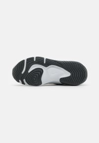 Mustan ja valkoisen värinen tennarin pohja, jossa on aaltoilevia kuvioita, näkyviä uria ja sileä valkoinen vaahtokappale. Nike-logo keskellä.