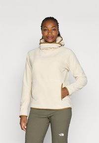 Beige fleece pullover met een hoge nek en bruine accenten; voorzien van zijzakken en een comfortabele pasvorm. Gestyled met olijfgroene broek.