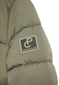 Kaki puffjacka med ärm som har en broderad logotyp med "Polo Club" och ett stiliserat "PC" emblemet i grönt på en mörk bakgrund.