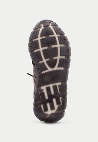 Černá gumová podrážka boty s texturovaným vzorem, který nabízí výraznou přilnavost a bílý lem. Název značky je vyražen na povrchu.