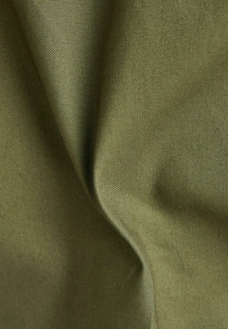 Tessuto verde oliva, trama strettamente tessuta, che mostra morbide pieghe e una finitura opaca, evidenziando la durata e la versatilità nel design.