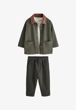 Olívazöld kabát barna kordbársony gallérral, patentos gombokkal, két elülső zsebbel, sötétzöld elasztikus derékpántos, húzózsinóros nadrággal párosítva.