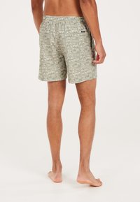 Geprinte zwemshorts in lichtgroen met een geometrisch ontwerp. Elastische tailleband, zijzakken en een lengte tot boven de knie. Zachte textuur.