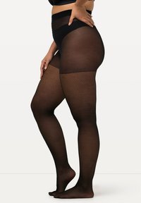 Collant in rete nera con vita alta e parte superiore trasparente. Un motivo texturizzato copre le gambe. Il materiale trasparente migliora la visibilità delle gambe.