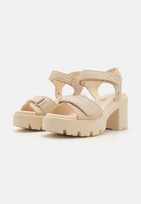 Beige Plateausandalen mit breiten Riemen, einer verstellbaren Schnalle und strukturierten Sohlen. Offene Zehenpartie mit Blockabsatz.