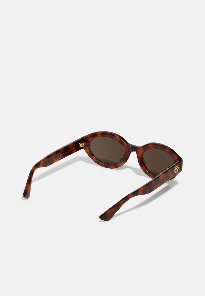 Schildpatt-Sonnenbrille mit ovalen braunen Gläsern, breiten Bügeln und einem goldenen Akzent nahe dem Gelenk, die eine glänzende Oberfläche und eine glatte Textur zeigen.