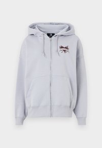 Sudadera gris con cremallera, bolsillo tipo canguro, capucha con cordón y logo bordado con un diseño de corazón y cinta.