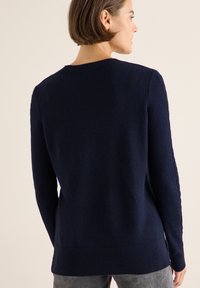 Dunkelblauer Strickpullover mit rundem Halsausschnitt, geripptem Saum und strukturierten Ärmeln mit Kabelstrickdetails.
