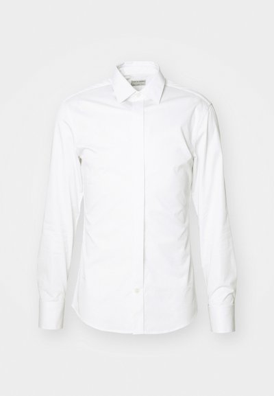 Valge pika varrukaga särk, mis on valmistatud siledast kangast, millel on tavaline krae, nööpide rida ja ümardatud äär, sobitades ideaalselt kehakujuga ning ilma mustriteta.