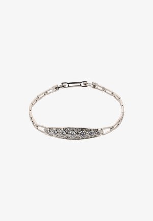 Ezüst karkötő, amelynek ívelt középpontjában több kerek, tiszta kő található, és bonyolult díszítéssel van ellátva egy lánc formájában.