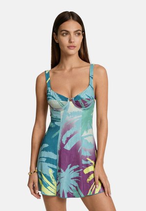 Donna con capelli lunghi e scuri che indossa un abito attillato senza maniche con fantasia tropicale nei colori blu, viola, verde e giallo.