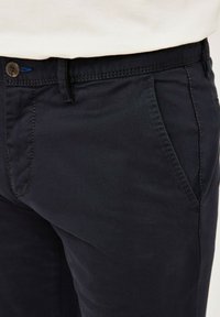 Dunkelmarineblaue Baumwollhosen mit Slim-Fit, ausgestattet mit Fronttaschen, einem Knopfverschluss und kontrastierenden Nähten.