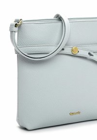 Jasnoniebieska skórzana torebka o uporządkowanym kształcie, wyposażona w złoty guzik oraz odpinany okrągły pasek. Gładka faktura.