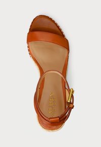 Sandal espadrillas in pelle marrone con due fasce larghe, una fibbia alla caviglia e una suola piattaforma in juta intrecciata. Texture liscia e opaca.