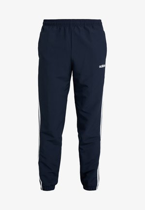 Pantalon de survêtement Adidas bleu marine avec ceinture élastique et poignets, bandes blanches sur les côtés et logo Adidas sur la cuisse gauche supérieure.