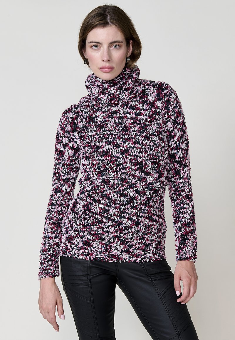 Pull en tricot avec un col haut, dans un motif tacheté de rose, violet et noir ; texture douce, manches longues et coupe ajustée.