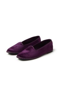 Un par de planos de terciopelo morado para mujer, con punteras redondeadas y suelas de goma negra cosidas, sobre un fondo blanco.