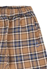 Bruine, blauwe en witte geruite broek met een elastische tailleband en een kleine geborduurde glimlach naast de zak.
