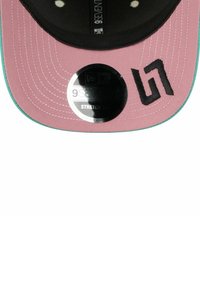 Czapka stretch-fit z czarną koroną, różowym daszkiem i kontrastującymi tealowymi przeszyciami. Z przodu znajduje się czarna haftowana logo.