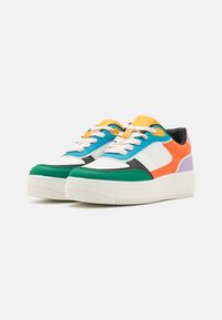 Colorful sneakers featuring a mix of materials: turquoise, white, orange, black, green, and purple accents with a thick white sole and textured detailing.