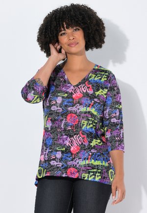 Top noir à col en V avec des manches trois-quarts, arborant un motif graffiti vibrant en rose, violet, bleu et vert sur un fond texturé.
