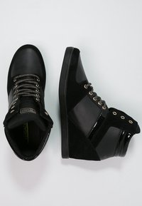 Baskets montantes noires en cuir et suède, avec des accents texturés, des œillets métalliques et un col rembourré.