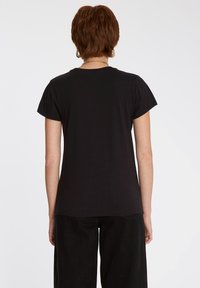 Zwarte t-shirt met korte mouwen van zachte katoen. Voorzien van een ronde halslijn en een relaxte pasvorm, met een licht gebogen zoom aan de achterkant.