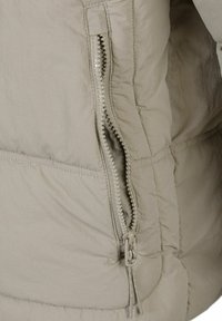 Lys beige pufferjakke sektion med en glat stofstruktur, vandret syninger og en nylon lynlås med en beskyttende flap.