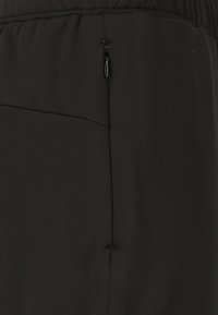 Svarta träningsbyxor som har ett mjukt material, elastisk midja och en sidoficka med dragkedja för säker förvaring. Minimalistisk design utan mönster.