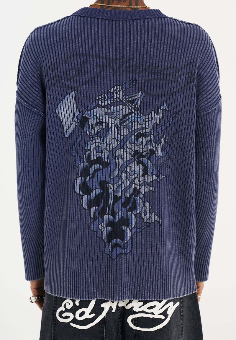Navy-blaues Rippenpullover mit langen Ärmeln, der einen grafischen Druck auf der Rückseite aufweist. Der Stoff hat ein strukturiertes Aussehen mit kontrastierenden Akzenten.